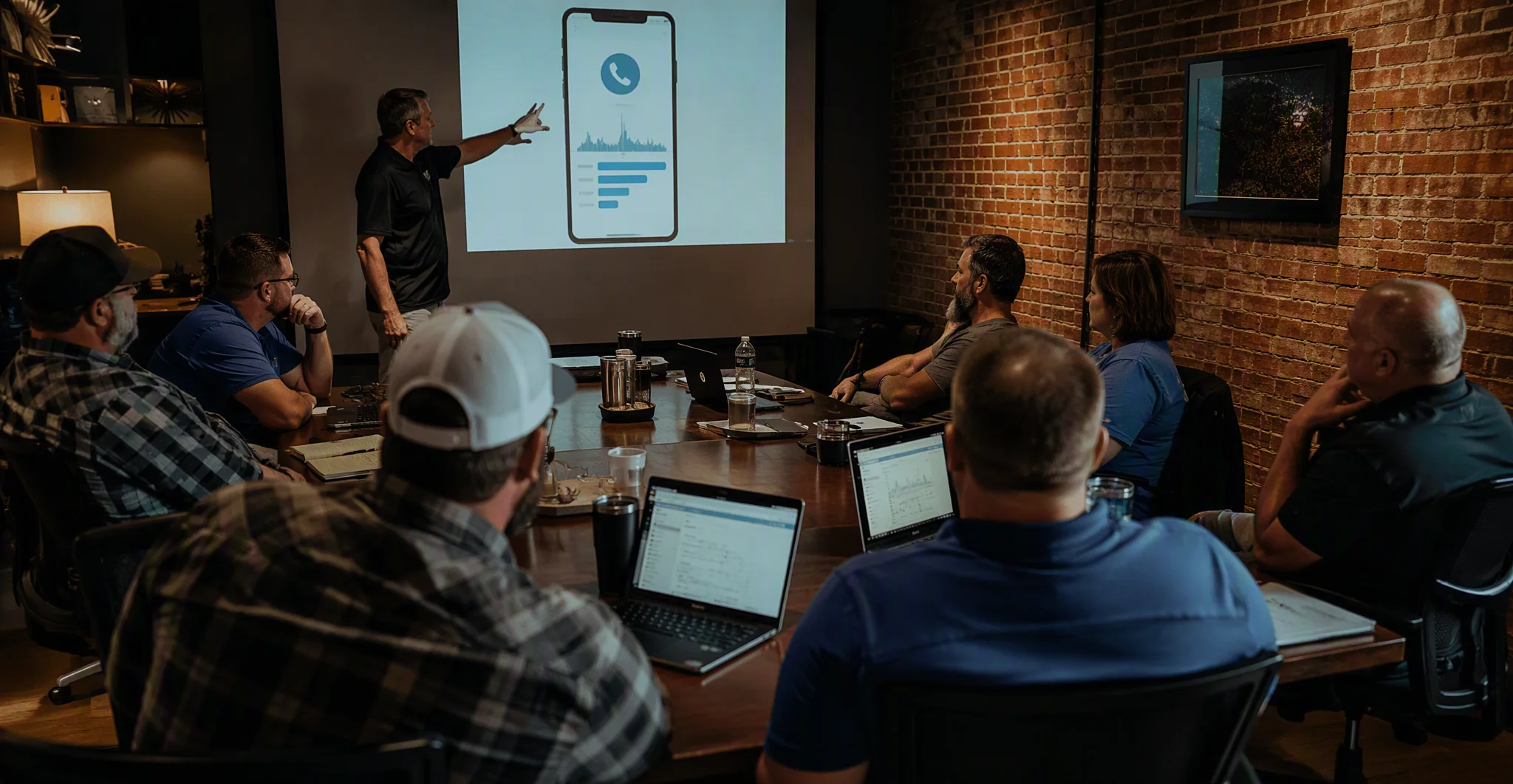 Facilitator demonstrating an AI phone dashboard to business owners seated around a workshop table